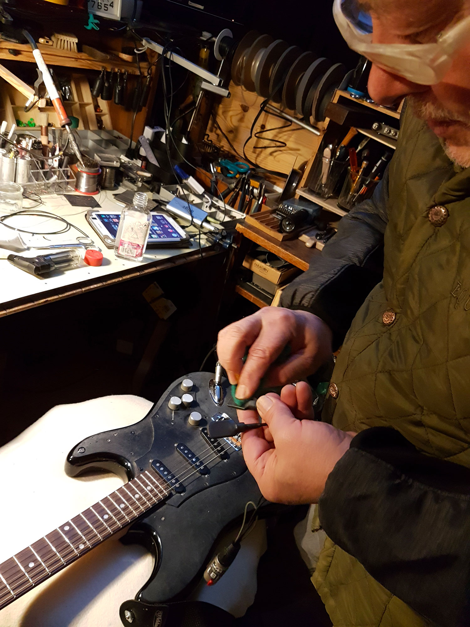 Un homme dans un atelier de musique installe un micro sur une guitare noire